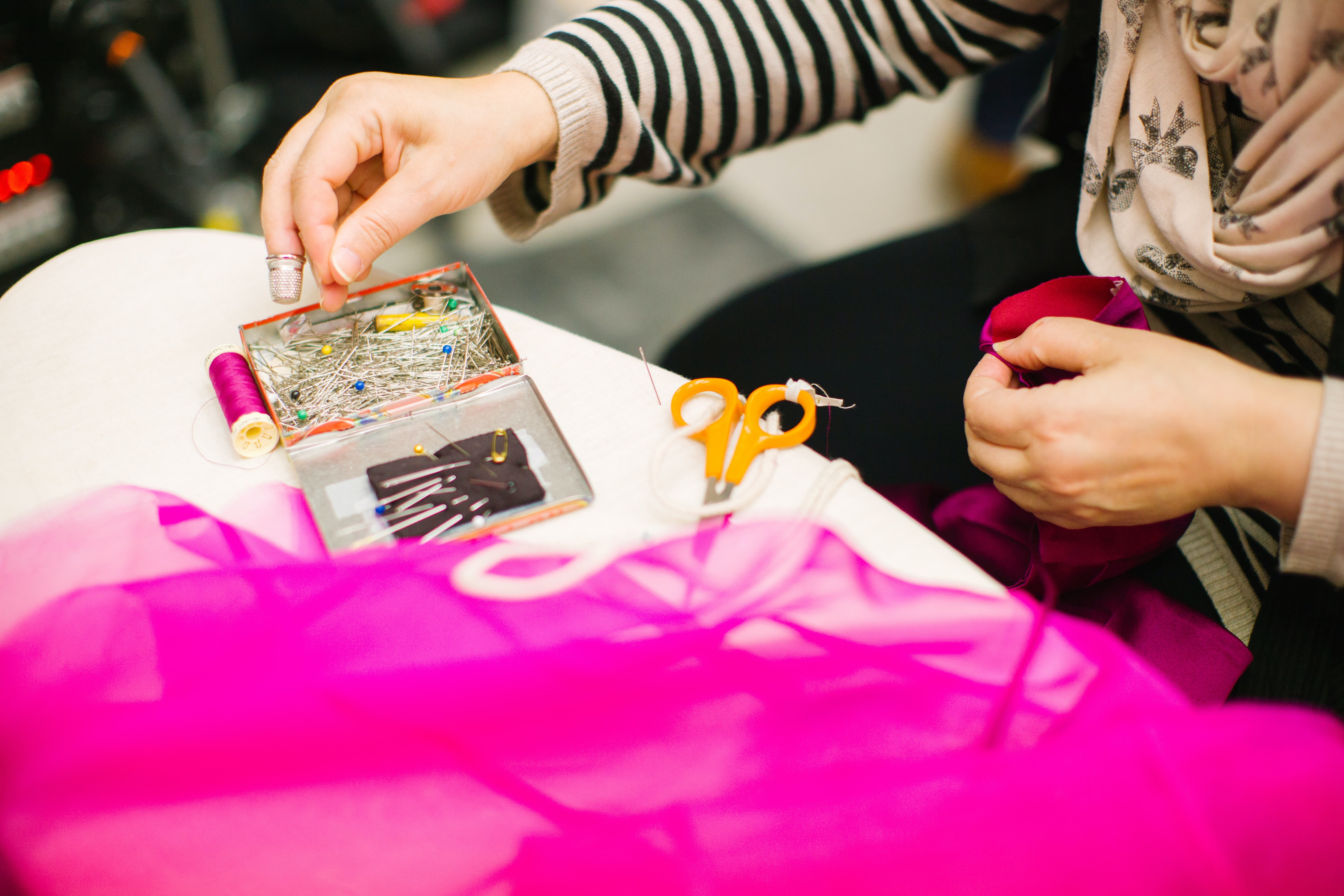 Woman sewing with pink net in the foreground